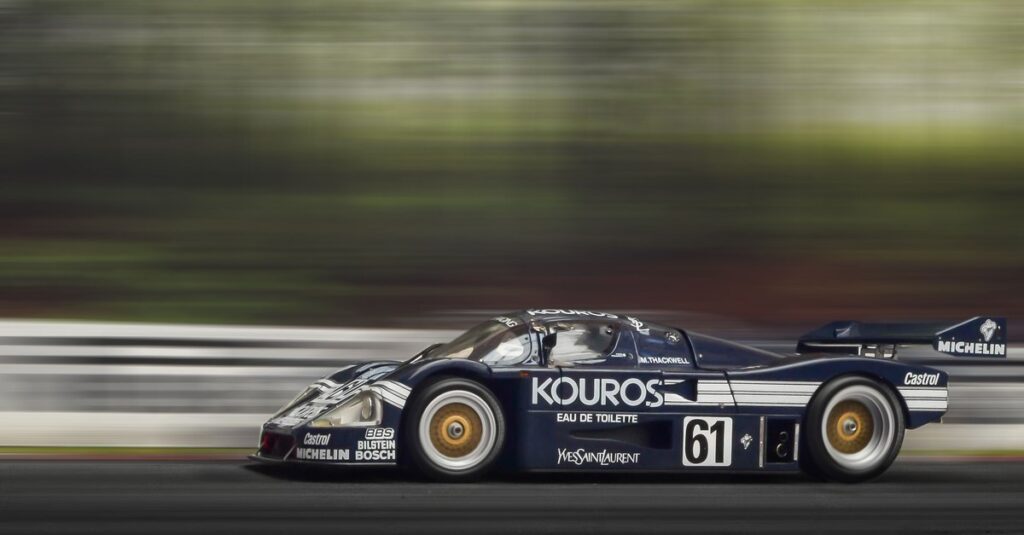 A race car at speed on a track, motion blurred, power committed to a line.