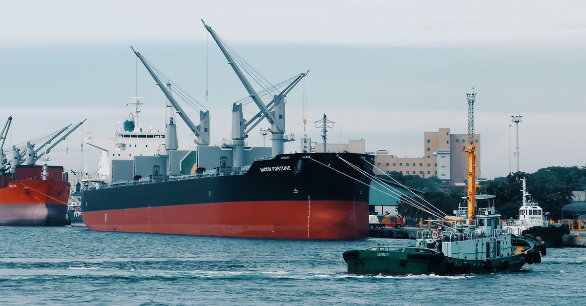 Tugboat steering a large container ship, a metaphor for leading through influence rather than authority.