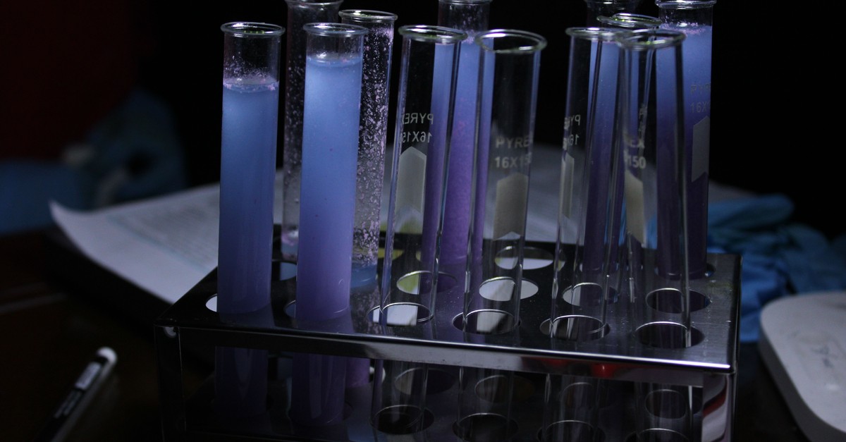 A row of laboratory test tubes holding a chemical experiment in progress, several tubes full and several empty.