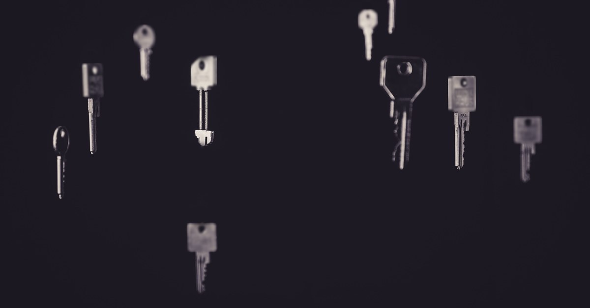 Loose metal keys of different shapes and sizes floating against a black background
